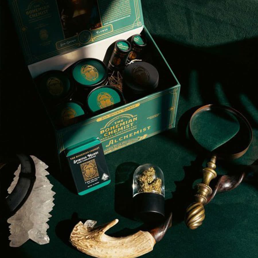 An assortment of The Bohemian Chemist cannabis products, including flower, pre-rolls, and concentrates, displayed on a green velvet background.
