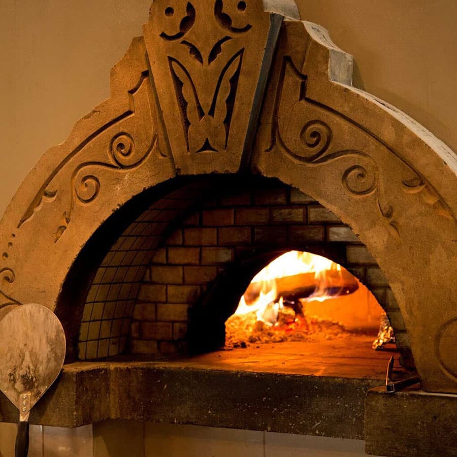 A wood-fired pizza oven with a flame burning inside.