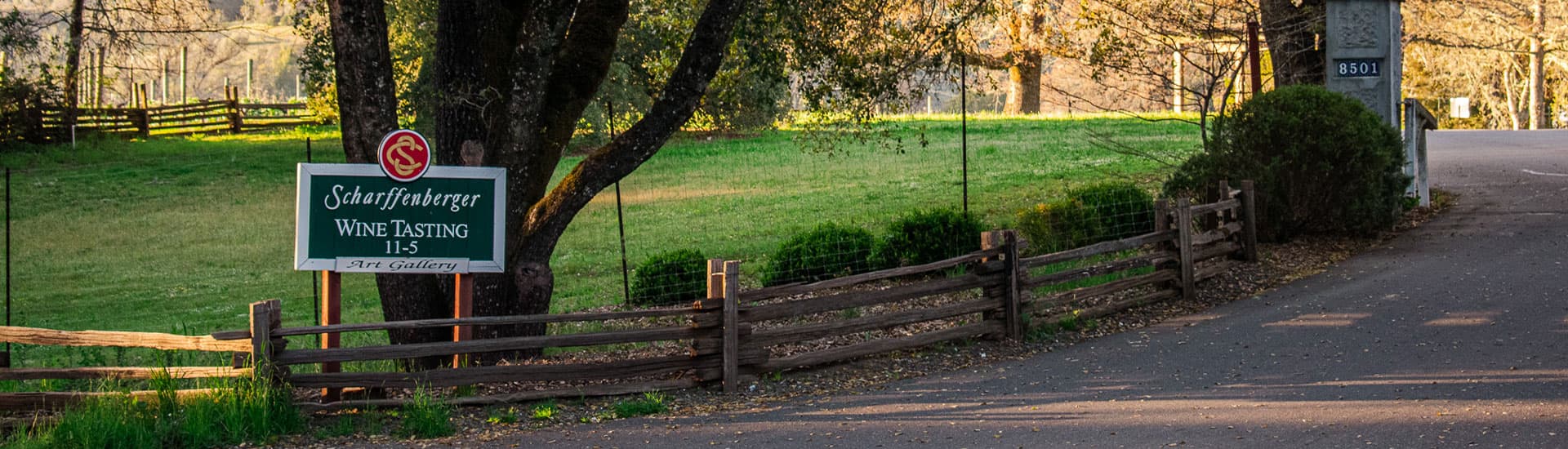 A sign advertising wine tasting at Scharffenberger Winery, with a scenic view of the vineyard in the background.