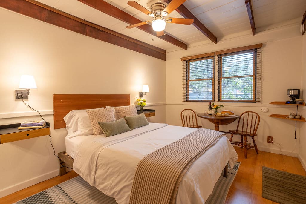 A bed with white sheets and pillows, a wooden headboard, a modern nightstands