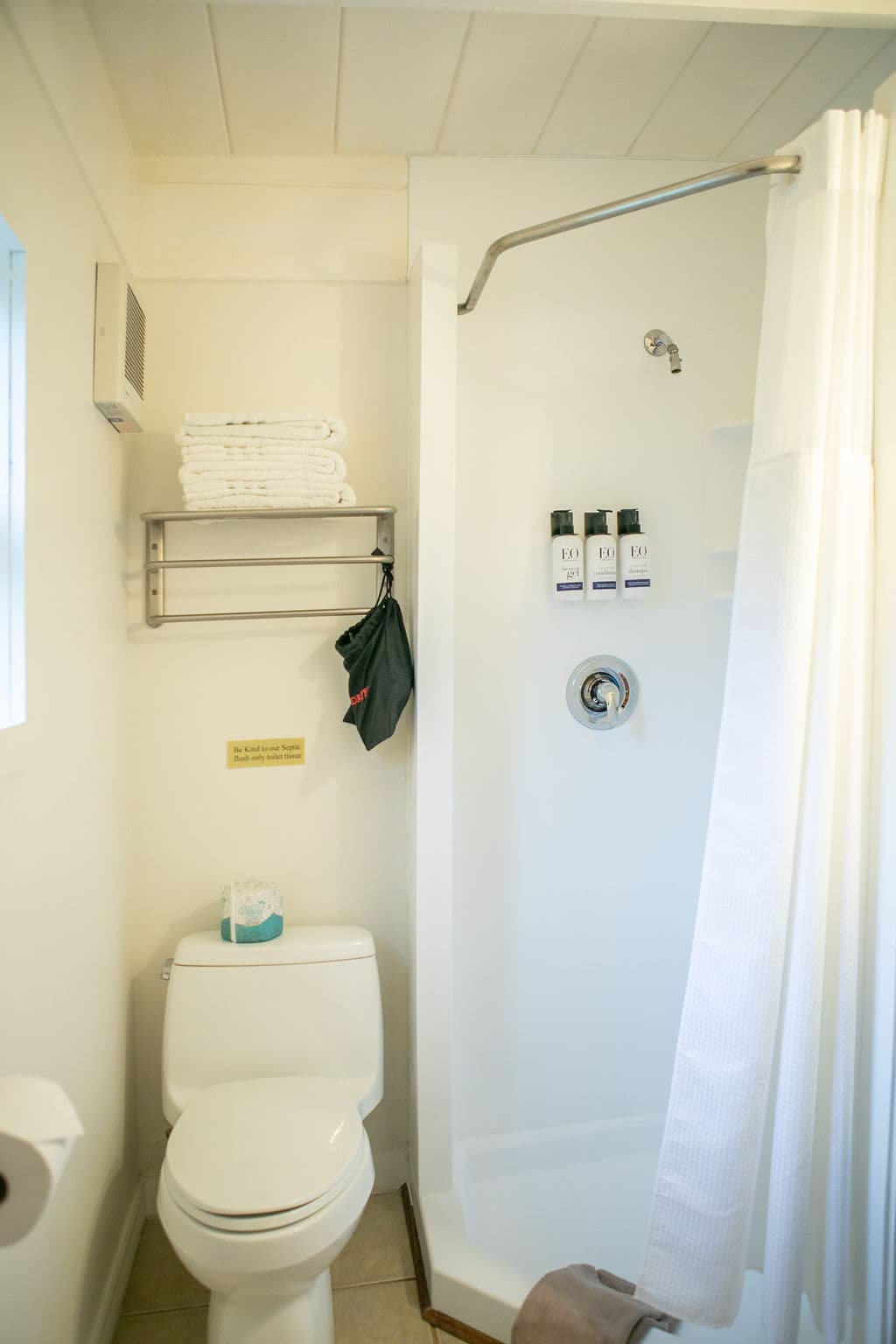 A clean, white bathroom with a shower, toilet, sink